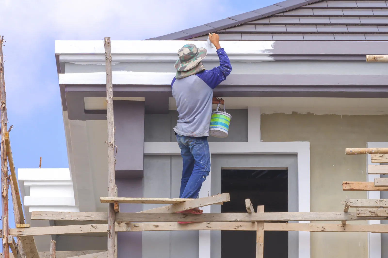 Painter on scaffolding painting a house exterior