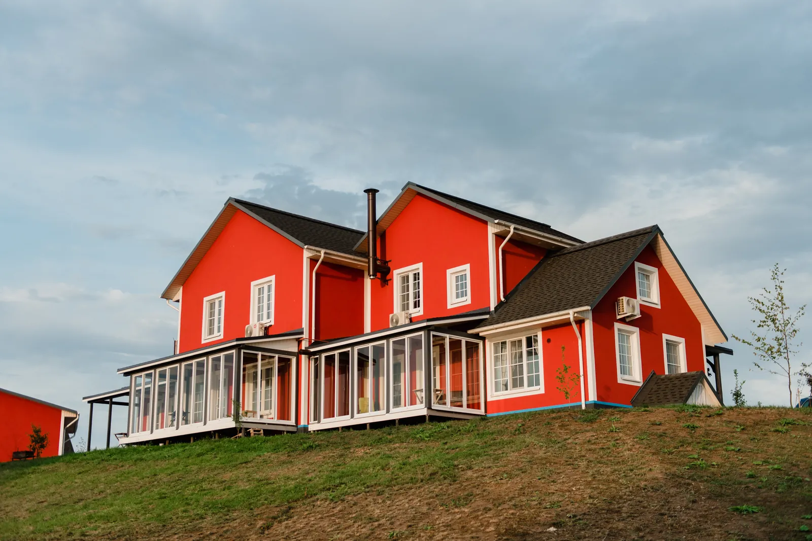 Wood-sided house with a solid red stain under a cloudy sky