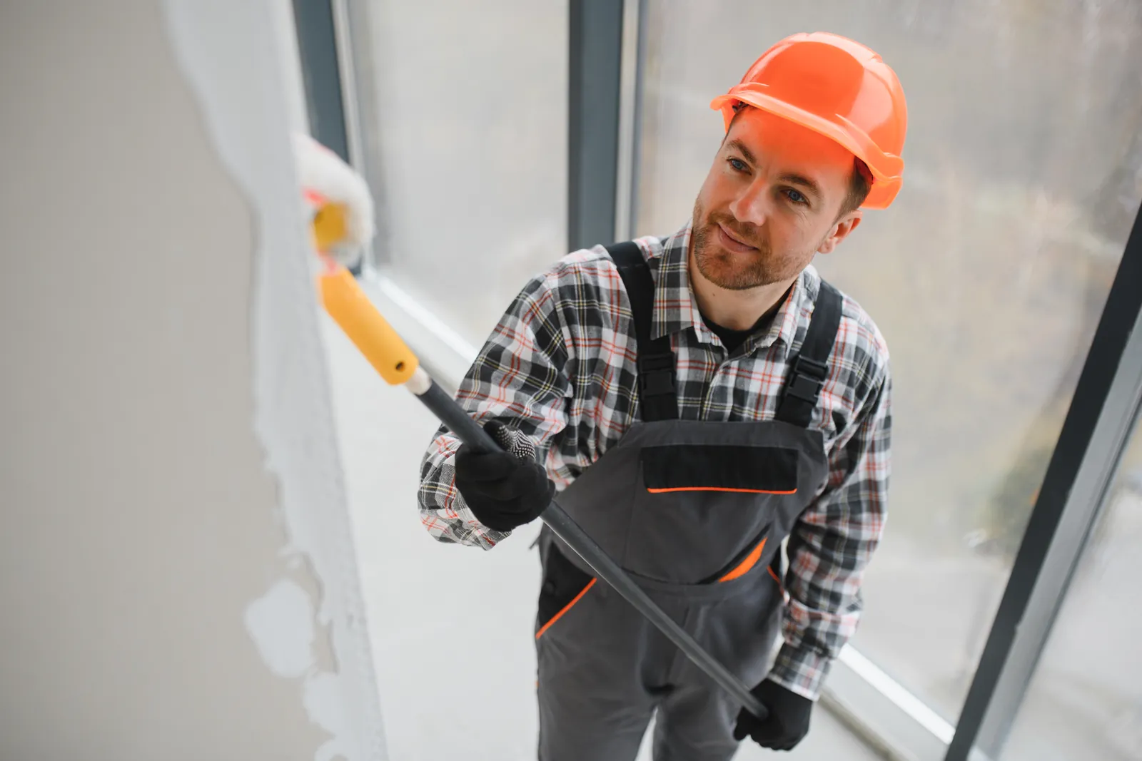 Painter applying a fresh coat to an office wall with a roller