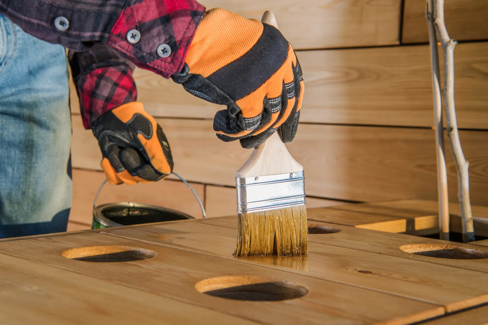 Hands brushing wood stain and protectant onto cedar boards